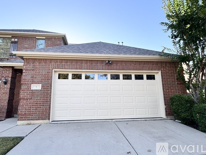 A house with a white garage door and a brick facade.