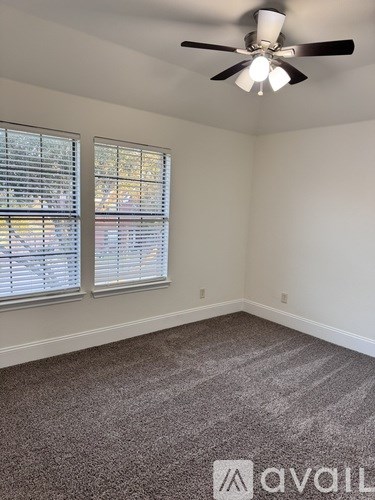 A room with a ceiling fan and two windows with blinds.