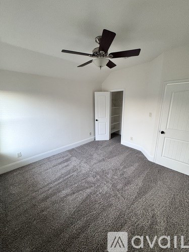 A room with a ceiling fan and carpeted floor.