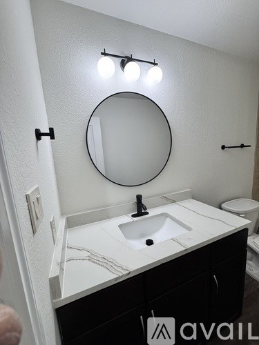 A bathroom with a round mirror and a sink.