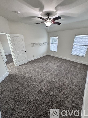 A room with a ceiling fan and carpeted floor.