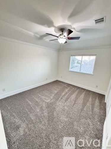 A room with a ceiling fan and carpeted floor.