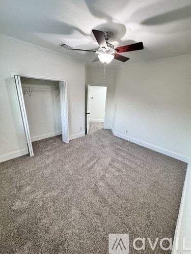 A room with a ceiling fan and carpeted floor.