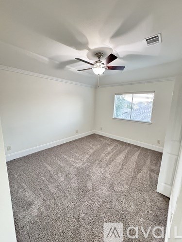 A room with a ceiling fan and carpeted floor.