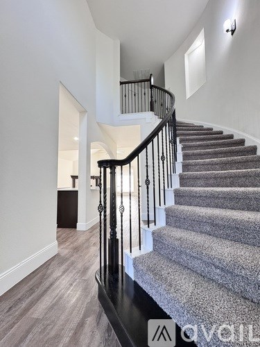 A staircase with a carpeted runner and black metal balusters.