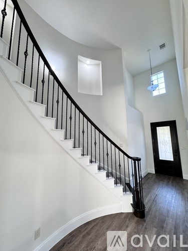 A staircase with a black railing and wooden steps leading to a door.