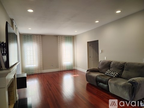A living room with a grey couch and wooden floors.