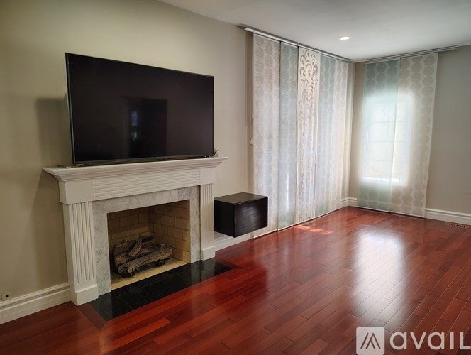 A black television is mounted above a fireplace in a room with wood flooring.