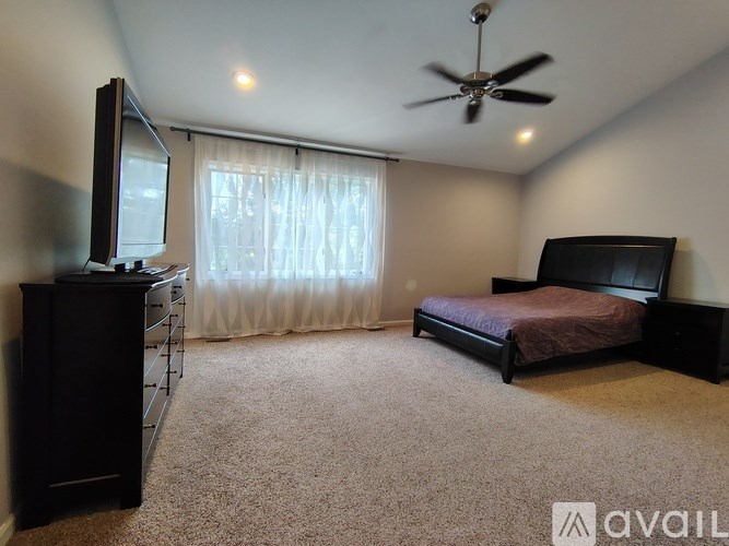 A bedroom with a bed, dresser, and television.