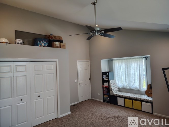 A room with a ceiling fan and a window with curtains.