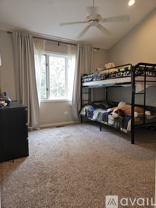 A room with a bunk bed, a dresser, and a window with curtains.