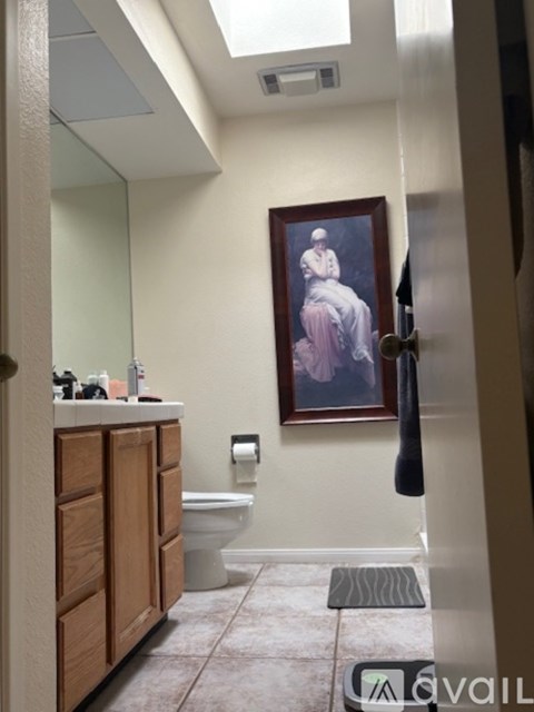 A bathroom with a toilet, sink, and a painting on the wall.