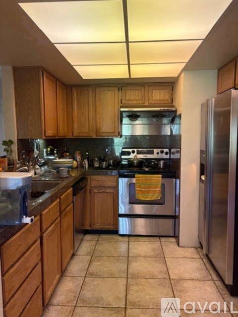 A kitchen with wooden cabinets and a stainless steel refrigerator.