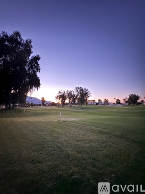 A golf course with a clear sky and trees in the distance.
