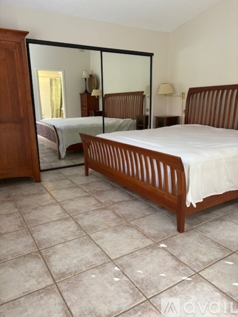 A bedroom with a large bed and a mirrored closet door.