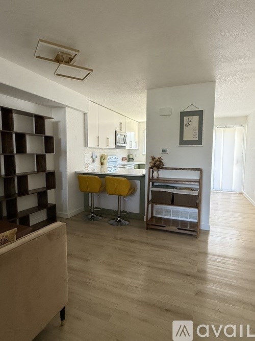 A kitchen with a yellow chair and a wooden floor.