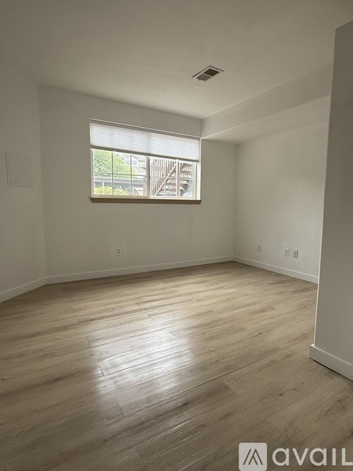 A room with wooden flooring and a window letting in natural light.
