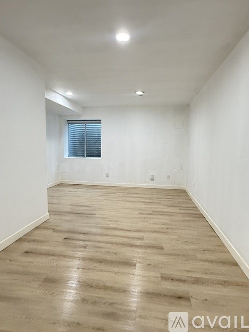 A room with wooden flooring and a window with blinds.