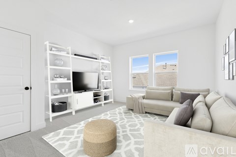 A living room with a white couch, a television, and a large window.