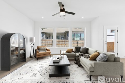 A modern living room with a grey sofa, a black coffee table, and a large window with a view of a building outside.