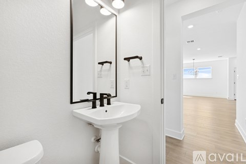 A bathroom with a white pedestal sink and a mirror above it.
