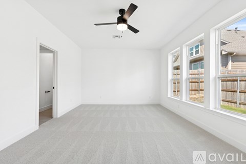 A room with a ceiling fan and carpeted floor.