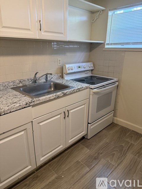 A kitchen with white cabinets and a white stove top oven.