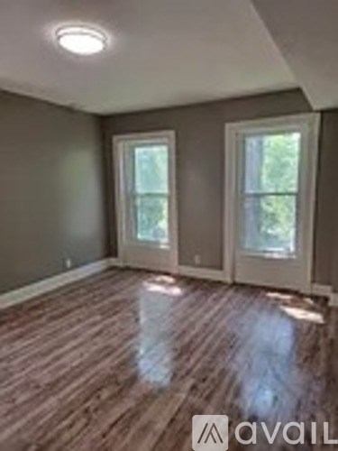A room with wooden floors and two windows.