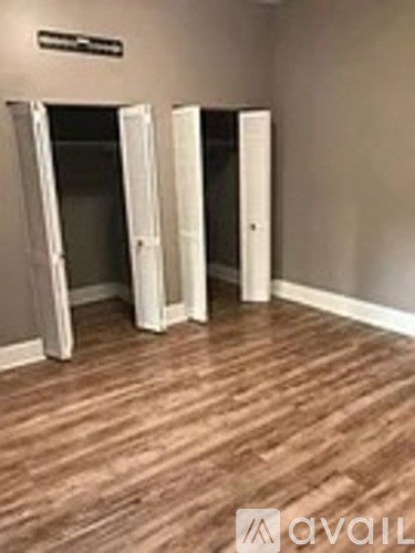 A room with a wooden floor and three open doors.