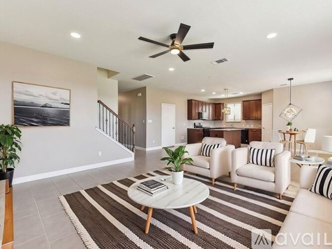 A living room with a striped rug and a ceiling fan.