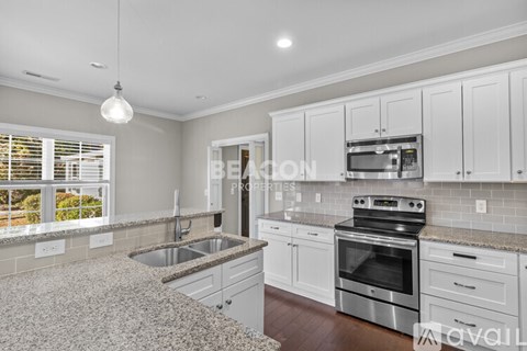 A modern kitchen with white cabinets and stainless steel appliances.