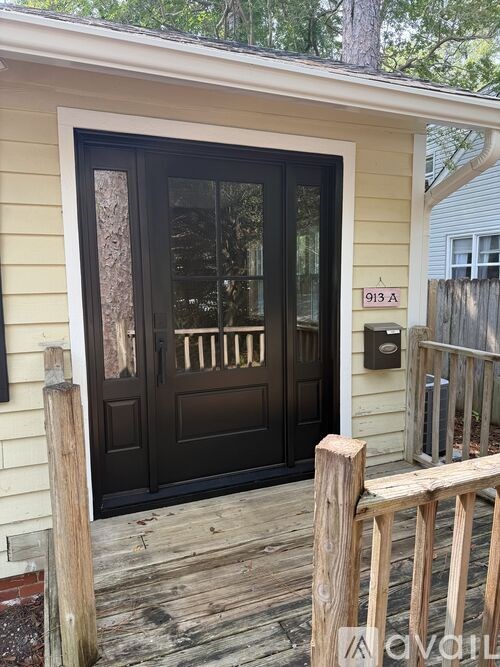 A black door with a glass window is on a yellow house.