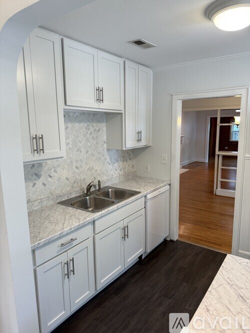 A kitchen with white cabinets and a marble backsplash.