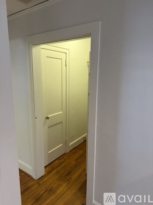 A white door is in a hallway with wood floors.