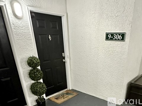 A black door with a welcome mat in front of it.