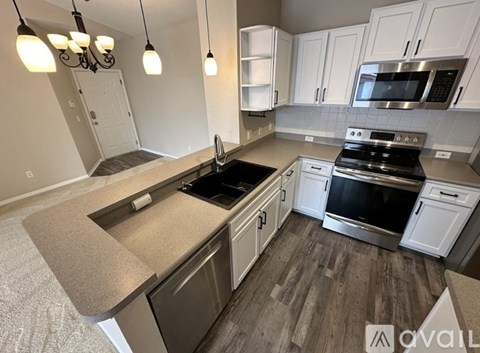 A kitchen with white cabinets and a wooden floor.