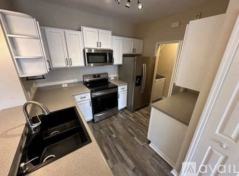 A kitchen with white cabinets and a black sink.