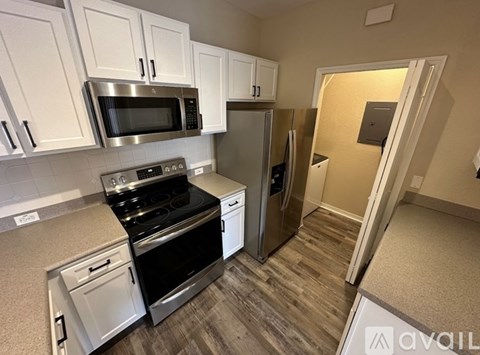 A kitchen with white cabinets and a stainless steel refrigerator.