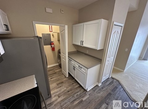 A kitchen with white cabinets and a grey fridge.