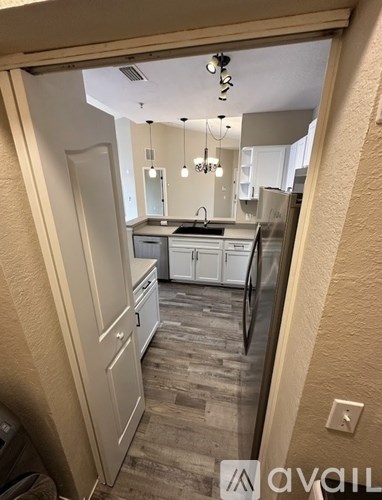 A kitchen with a white fridge and cabinets, a sink, and a dishwasher.