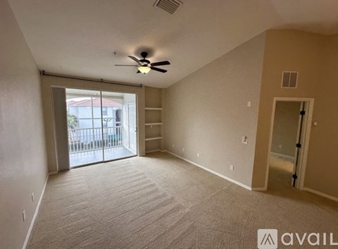 A room with a ceiling fan and a sliding glass door leading to a balcony.