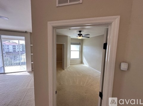 A room with a ceiling fan and a door leading to another room.