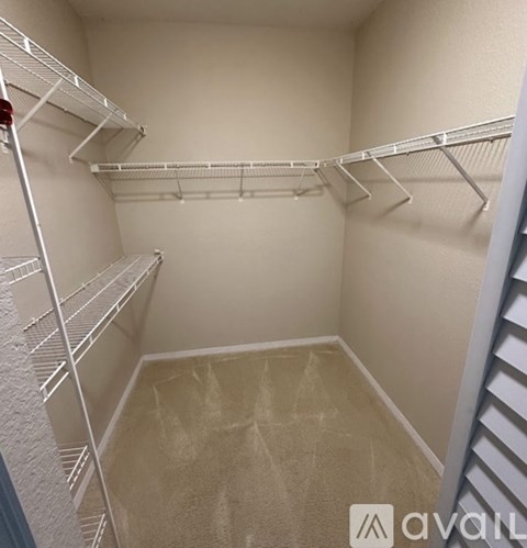 A small, empty walk-in closet with white shelving.