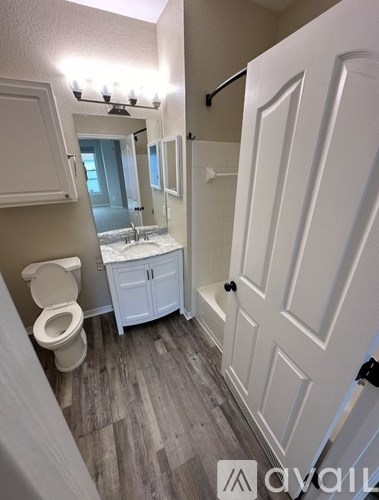A bathroom with a toilet, sink, and mirror.