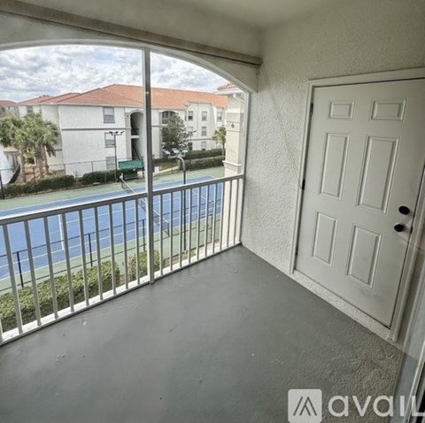 A balcony with a white door and a view of a pool and buildings.