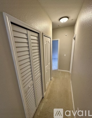 A hallway with a carpeted floor and white walls.