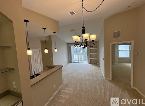 A spacious room with a chandelier and a carpeted floor.