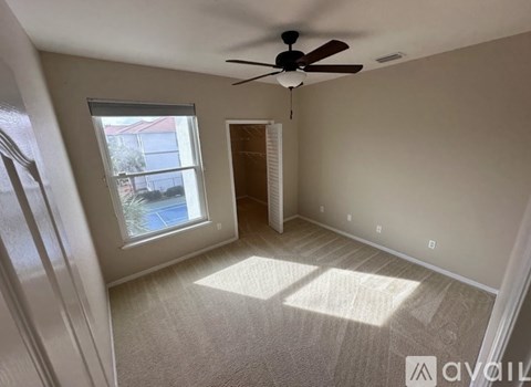A room with a ceiling fan and a window overlooking a pool.