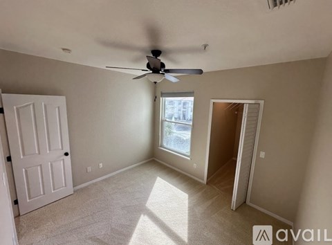 A room with a ceiling fan and a window letting in sunlight.