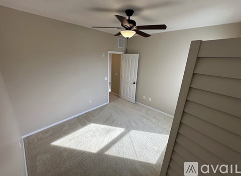 A room with a ceiling fan and a door leading to another room.